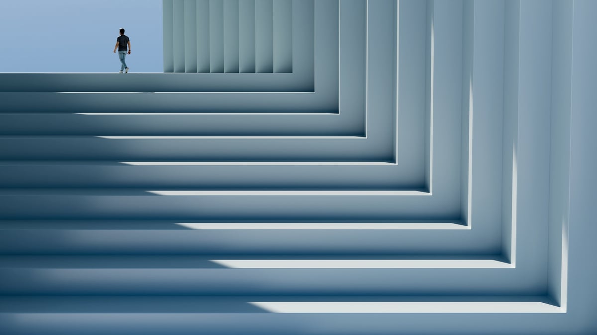 Persona caminando sobre una gran escalinata con columnas y luz, simbolizando logro y visión corporativa